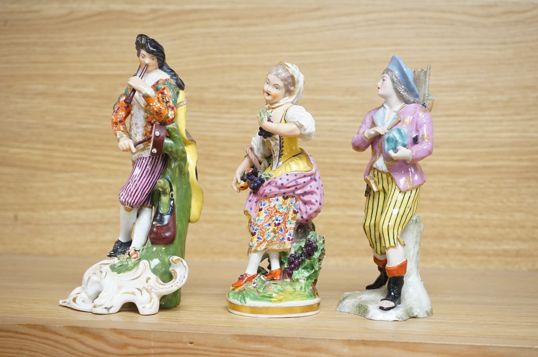 Three late 18th century Derby figures, a similar Derby figure of Summer, c.1810–30 and a Derby style figure of a street vendor, tallest 26cm high